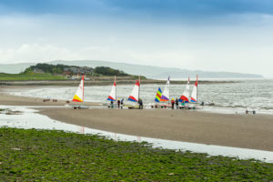 A group of Topper dinghies get ready to launch from the beach