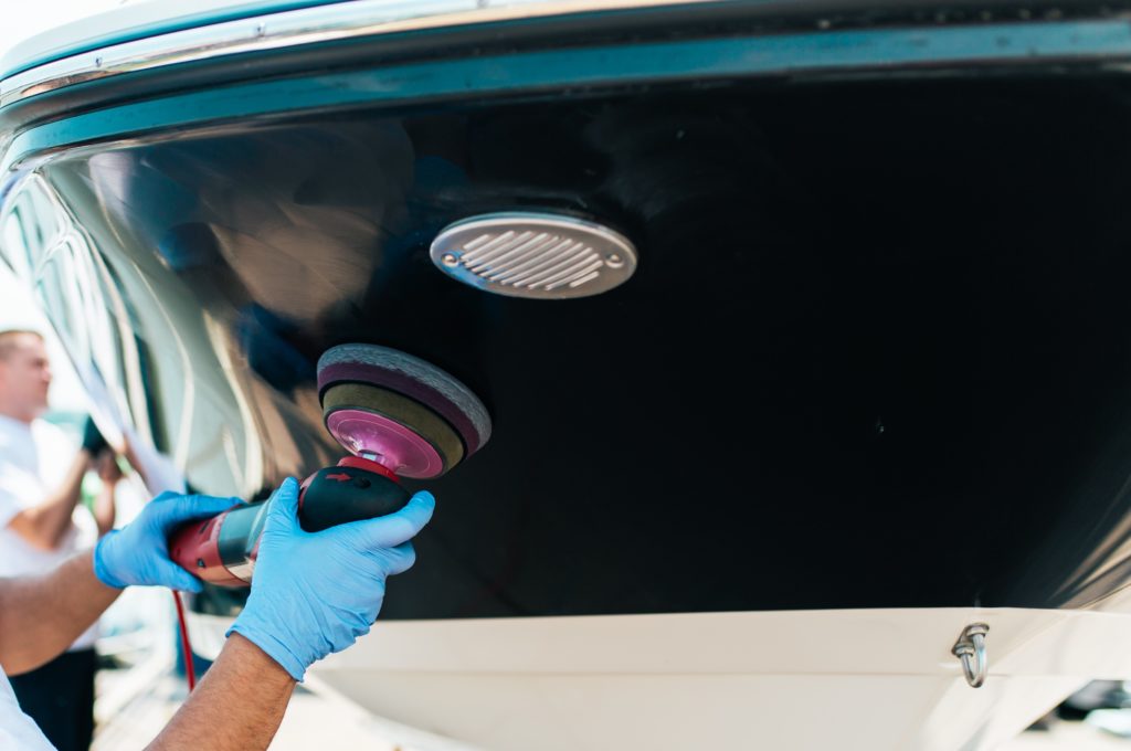 Boat valeter polishing the topsides of the hull of a speedboat using 3M/Ferecla products