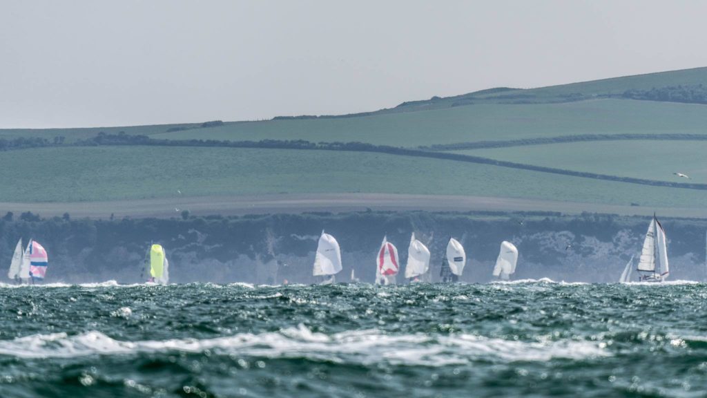 Yachts racing in Poole Regatta 2022. Poole Bay with the purbeck hills in the background